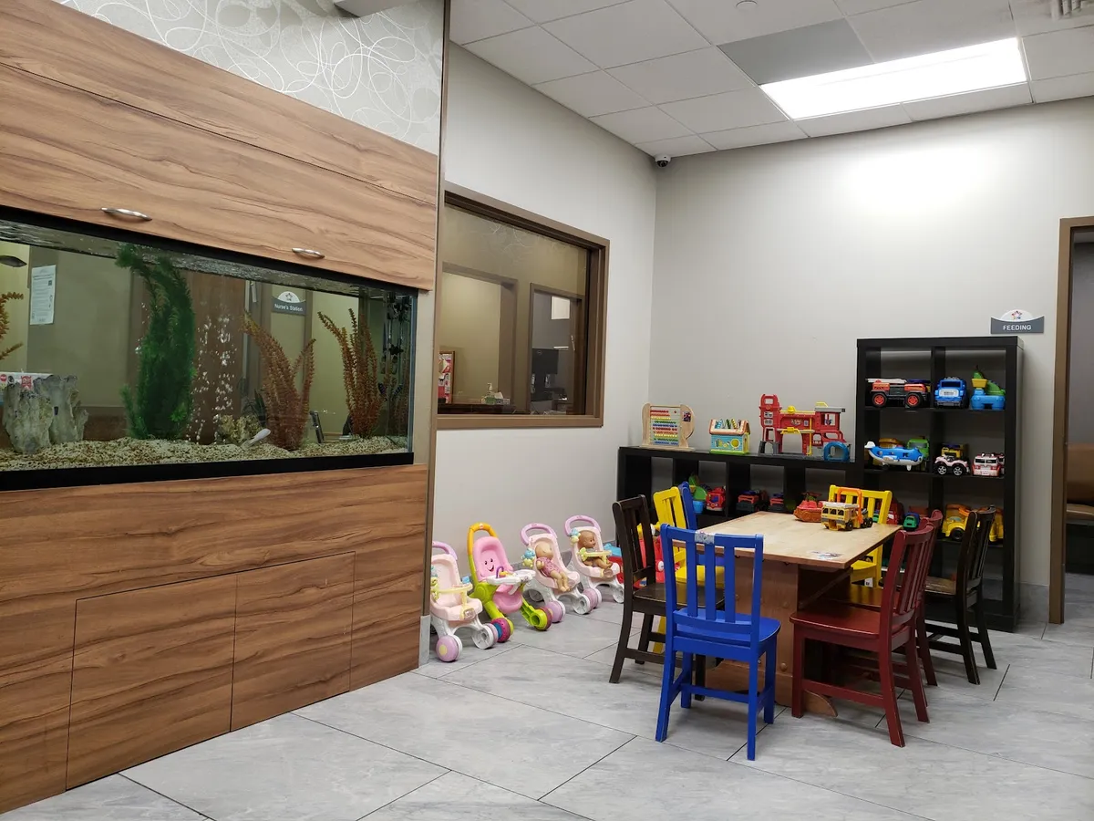 The Monsey waiting room: a fish tank set into a wood wall, small chairs and ride-on toys