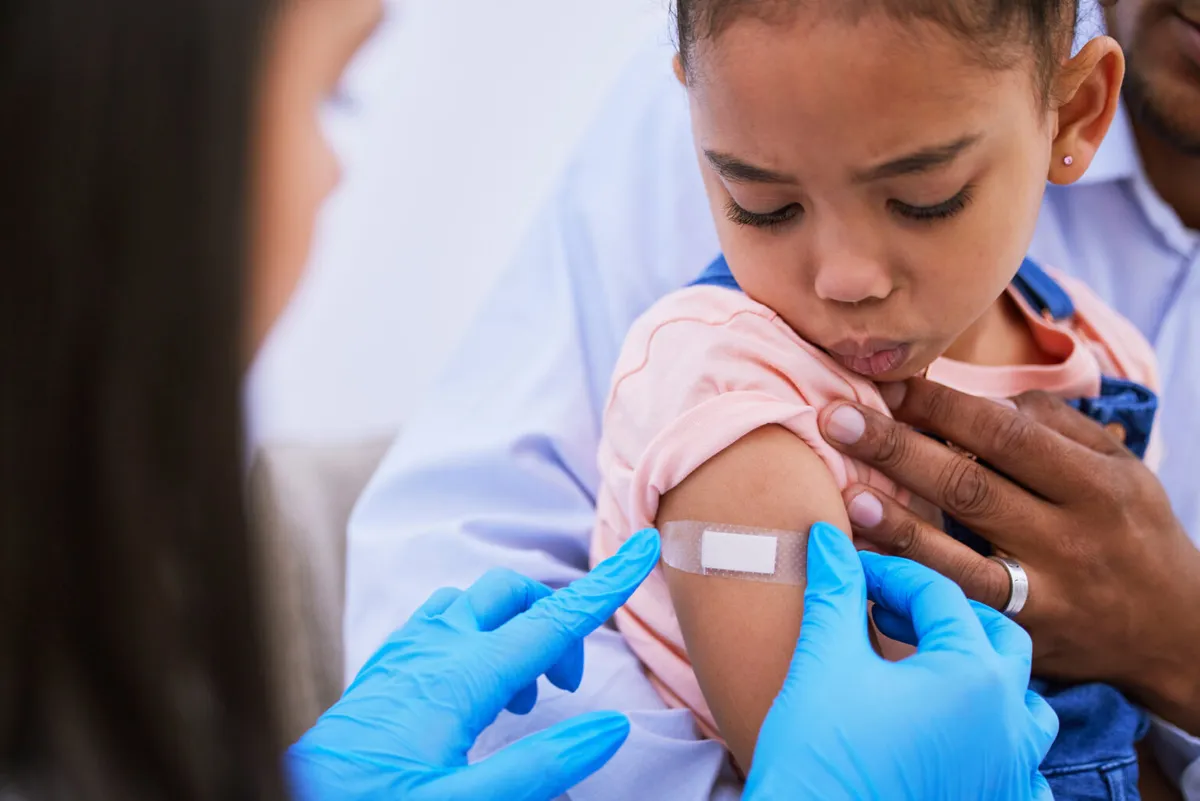 A girl looking at the bandage on her arm after a vaccine
